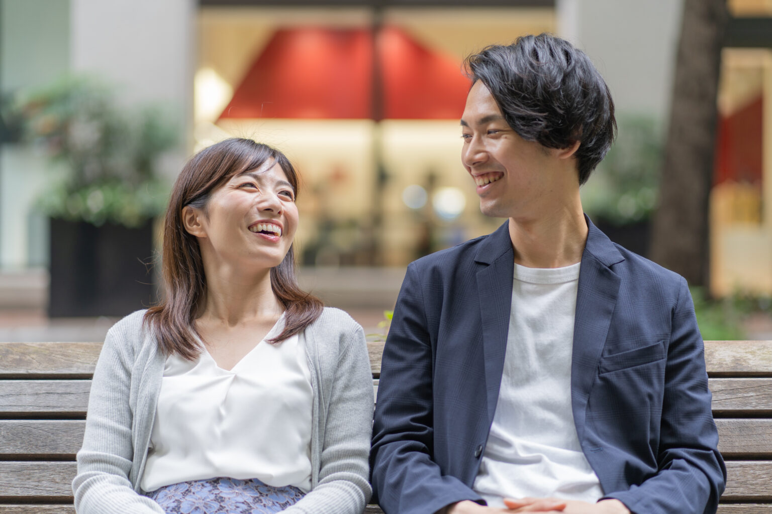 ベンチに並んで笑いながら話す30代の男女
